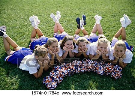 Stock Image - High angle view of cheerleaders lying on a lawn. Fotosearch