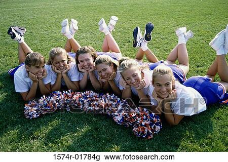 Stock Image - High angle view of cheerleaders lying on a lawn. Fotosearch