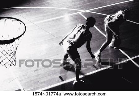 Stock Image - High angle view of two young women playing basketball. Fotosearch