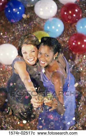 Stock Image - High angle view of two young women holding champagne flutes. Fotosearch