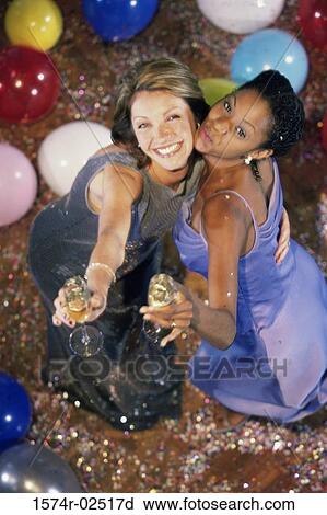 High angle view of two young women holding champagne flutes View Large Photo Image Stock Image - High angle view of two young women holding champagne flutes. Fotosearch
