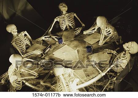 Stock Image - Human skeletons covered in cobwebs at a meeting. Fotosearch