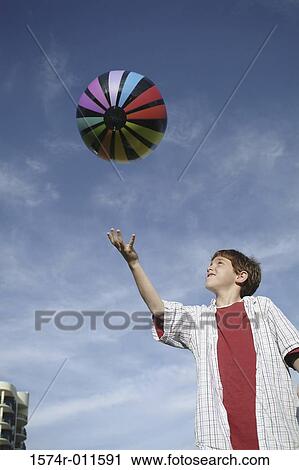 Stock Image - Low angle view of a boy playing with a ball. Fotosearch