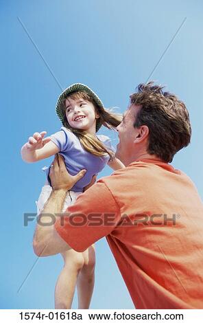 Stock Image - Low angle view of a daughter thrown up in the air by her father. Fotosearch