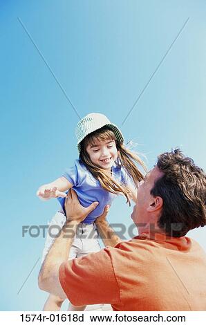 Stock Image - Low angle view of a daughter thrown up in the air by her father. Fotosearch