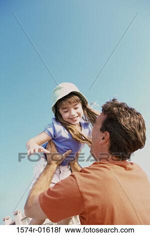 Low angle view of a daughter thrown up in the air by her father View Large Photo Image Stock Image - Low angle view of a daughter thrown up in the air by her father. Fotosearch