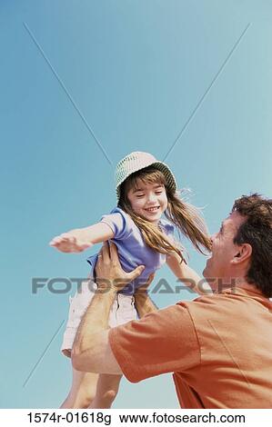 Low angle view of a daughter thrown up in the air by her father View Large Photo Image Stock Image - Low angle view of a daughter thrown up in the air by her father. Fotosearch