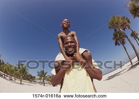 Low angle view of a father carrying his son on his shoulders View Large Photo Image Stock Image - Low angle view of a father carrying his son on his shoulders. Fotosearch