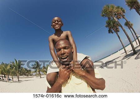 Low angle view of a father carrying his son on his shoulders View Large Photo Image Stock Image - Low angle view of a father carrying his son on his shoulders. Fotosearch