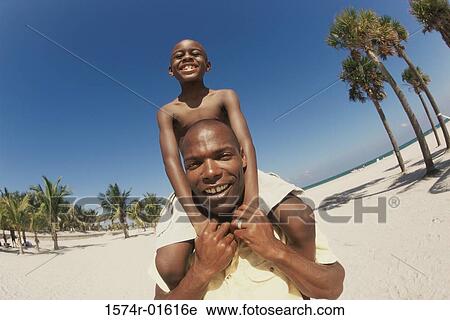 Low angle view of a father carrying his son on his shoulders View Large Photo Image Stock Image - Low angle view of a father carrying his son on his shoulders. Fotosearch