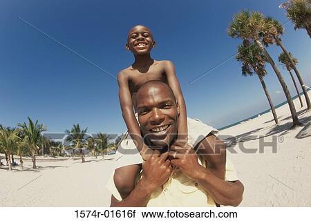 Low angle view of a father carrying his son on his shoulders View Large Photo Image Stock Image - Low angle view of a father carrying his son on his shoulders. Fotosearch