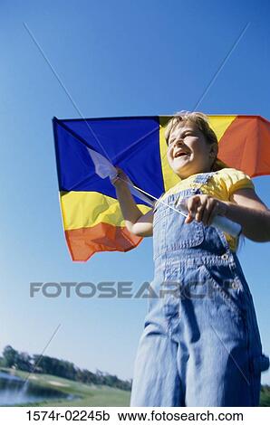 Low angle view of a girl holding a kite View Large Photo Image Stock Image - Low angle view of a girl holding a kite. Fotosearch