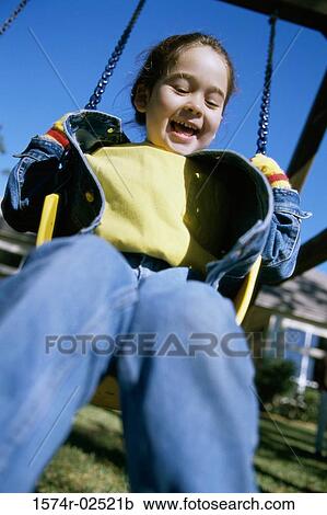 Stock Image - Low angle view of a girl sitting on a swing. Fotosearch
