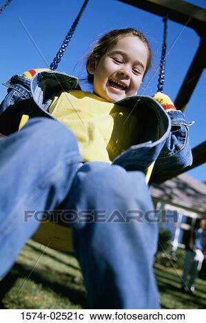Low angle view of a girl sitting on a swing View Large Photo Image Stock Image - Low angle view of a girl sitting on a swing. Fotosearch