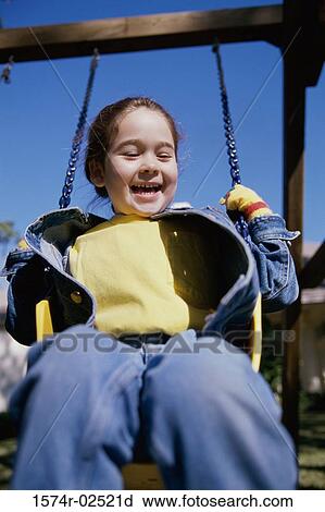 Stock Image - Low angle view of a girl sitting on a swing. Fotosearch