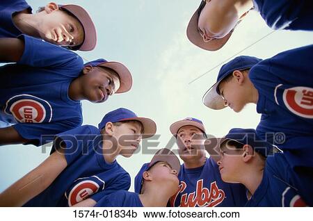 Stock Image - Low angle view of a little league baseball team in a huddle with their coach. Fotosearch