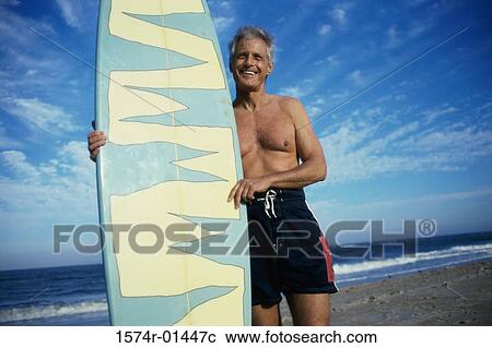 Low angle view of a senior man holding a surfboard View Large Photo Image Stock Image - Low angle view of a senior man holding a surfboard. Fotosearch