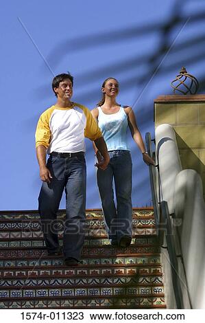 Stock Image - Low angle view of a young couple walking down stairs. Fotosearch