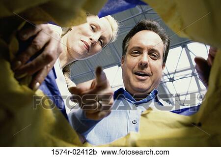 Stock Image - Low angle view of a young couple looking into a shopping bag. Fotosearch