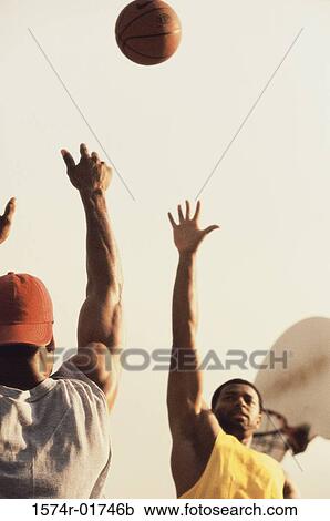 Stock Image - Low angle view of two men playing basketball. Fotosearch