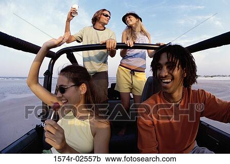 Stock Image - Low angle view of two young couples in a jeep. Fotosearch