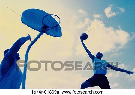 Low angle view of two young men playing basketball View Large Photo Image Stock Image - Low angle view of two young men playing basketball. Fotosearch
