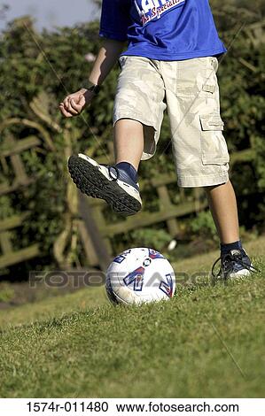 Stock Image - Low section view of a boy playing soccer. Fotosearch