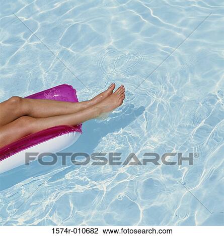Stock Image - Low section view of a person floating on a inflatable raft. Fotosearch