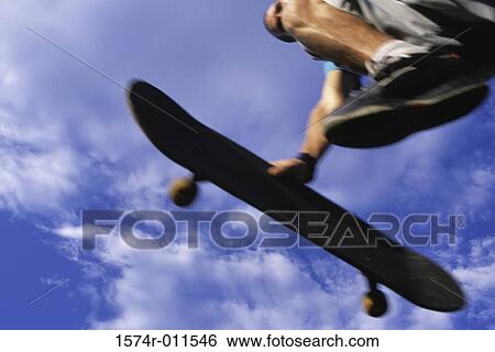 Stock Photograph - Low section view of a young man skateboarding. Fotosearch
