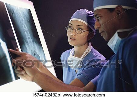 Stock Image - Male doctor and a female doctor examining an x-ray report. Fotosearch