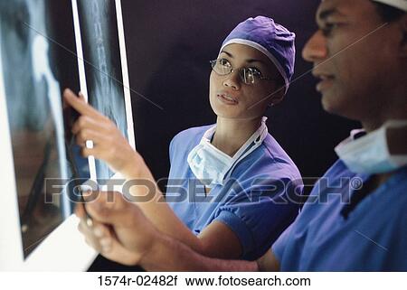 Stock Image - Male doctor and a female doctor examining an x-ray report. Fotosearch