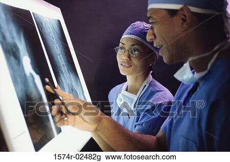 Stock Image - Male doctor and a female doctor examining an x-ray report. Fotosearch