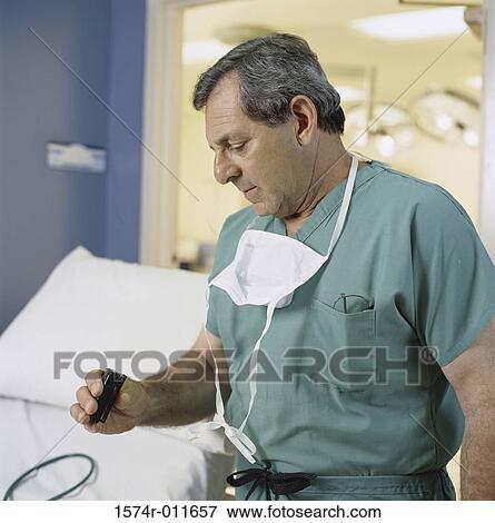 Male surgeon reading his pager View Large Photo Image Stock Photo - Male surgeon reading his pager. Fotosearch