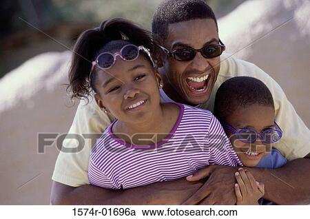 Stock Image - Man hugging his son and daughter on the beach. Fotosearch