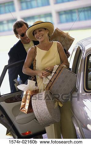 Mature woman exiting a car with shopping bags View Large Photo Image Stock Image - Mature woman exiting a car with shopping bags. Fotosearch