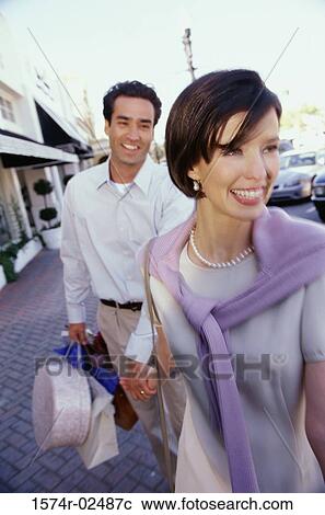 Stock Image - Mid adult couple carrying shopping bags. Fotosearch