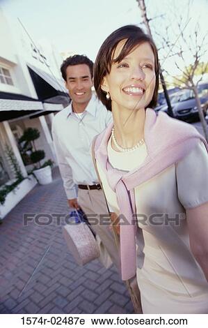Stock Image - Mid adult couple carrying shopping bags. Fotosearch