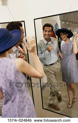 Mid adult couple standing in front of a mirror in the fitting room of a clothing store View Large Photo Image Stock Image - Mid adult couple standing in front of a mirror in the fitting room of a clothing store. Fotosearch