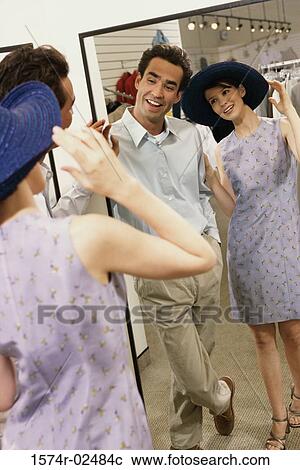 Mid adult couple standing in front of a mirror in the fitting room of a clothing store View Large Photo Image Stock Image - Mid adult couple standing in front of a mirror in the fitting room of a clothing store. Fotosearch