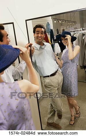 Mid adult couple standing in front of a mirror in the fitting room of a clothing store View Large Photo Image Stock Image - Mid adult couple standing in front of a mirror in the fitting room of a clothing store. Fotosearch