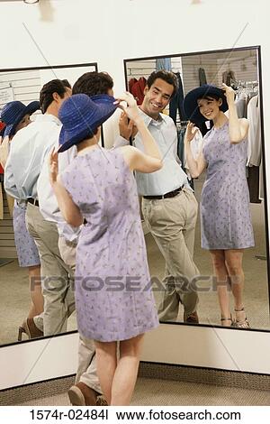 Mid adult couple standing in front of a mirror in the fitting room of a clothing store View Large Photo Image Stock Image - Mid adult couple standing in front of a mirror in the fitting room of a clothing store. Fotosearch