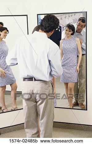 Mid adult couple standing in front of a mirror in the fitting room of a clothing store View Large Photo Image Stock Image - Mid adult couple standing in front of a mirror in the fitting room of a clothing store. Fotosearch