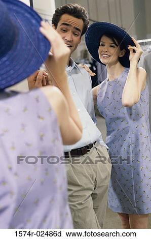 Mid adult couple standing in front of a mirror in the fitting room of a clothing store View Large Photo Image Stock Image - Mid adult couple standing in front of a mirror in the fitting room of a clothing store. Fotosearch