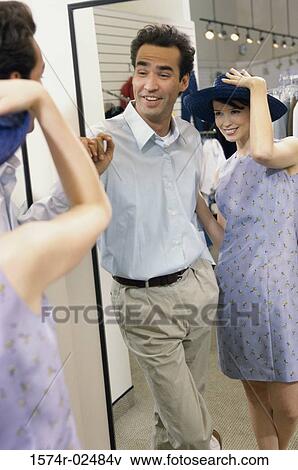 Mid adult couple standing in front of a mirror in the fitting room of a clothing store View Large Photo Image Stock Photo - Mid adult couple standing in front of a mirror in the fitting room of a clothing store. Fotosearch