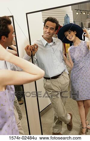 Mid adult couple standing in front of a mirror in the fitting room of a clothing store View Large Photo Image Stock Photograph - Mid adult couple standing in front of a mirror in the fitting room of a clothing store. Fotosearch