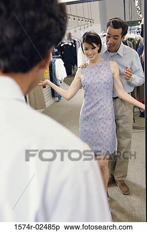 Mid adult couple standing in front of a mirror in the fitting room of a clothing store View Large Photo Image Stock Photography - Mid adult couple standing in front of a mirror in the fitting room of a clothing store. Fotosearch