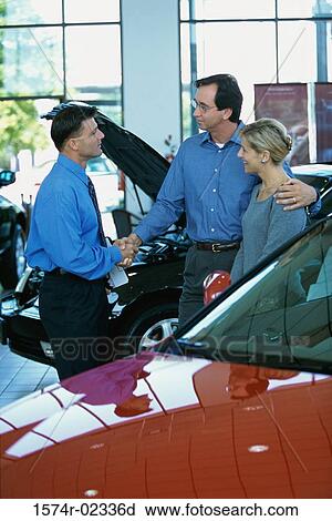 Mid adult couple talking to a car salesman in a car showroom View Large Photo Image Stock Image - Mid adult couple talking to a car salesman in a car showroom. Fotosearch