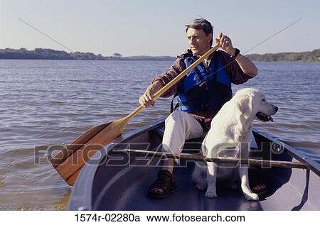 Stock Image - Mid adult man in a row boat with his dog. Fotosearch