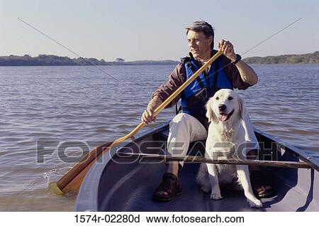 Stock Image - Mid adult man in a row boat with his dog. Fotosearch