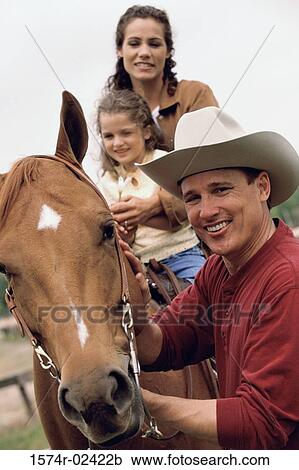 Stock Image - Mother and her daughter sitting on a horse. Fotosearch